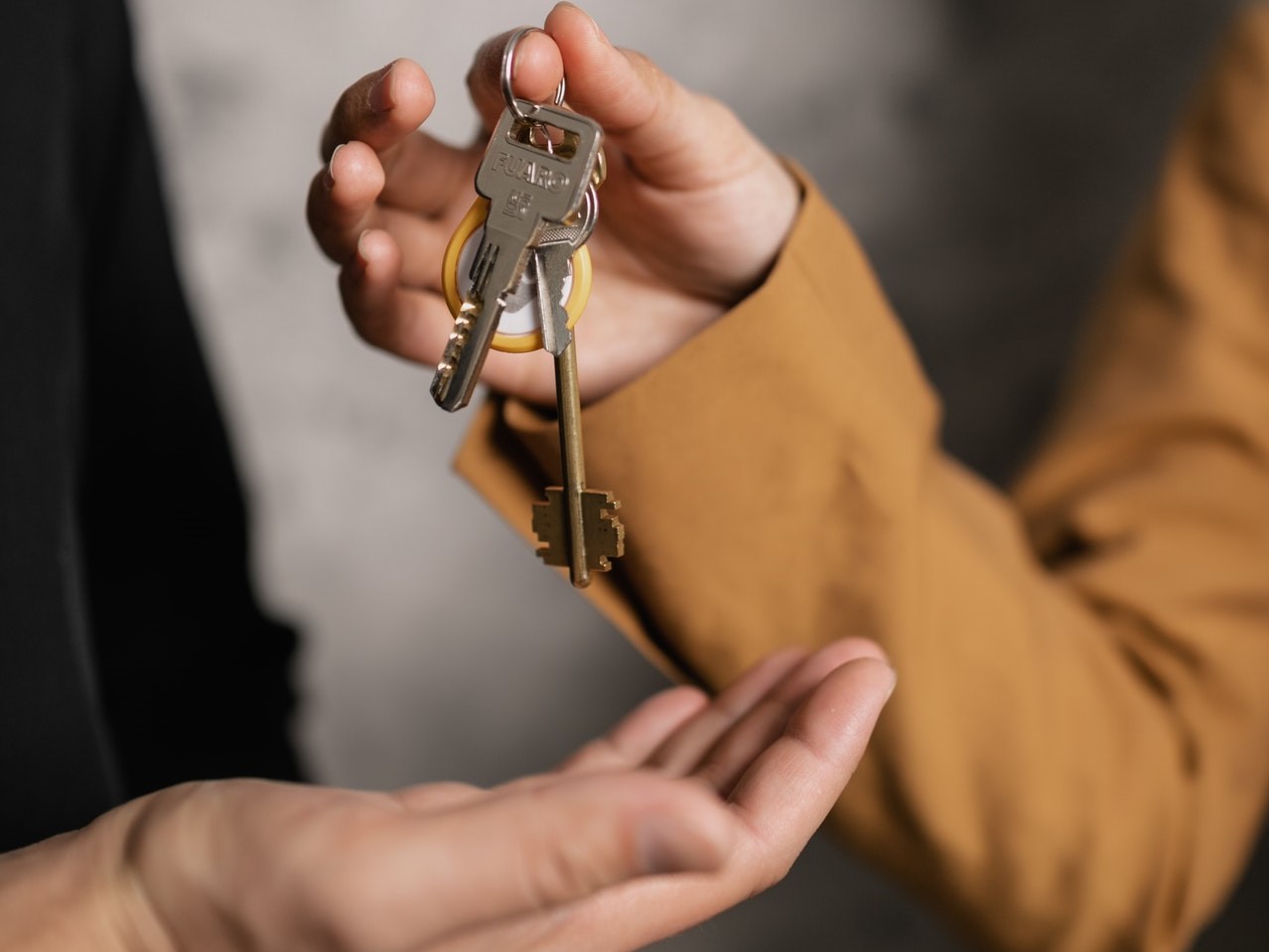 woman handing house keys to man | sell your home in less time with less stress | the gahm real estate team | boerne texas